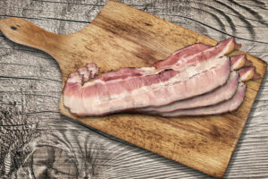 Cutting Board With Pork Belly Bacon Rashers on Wooden Background